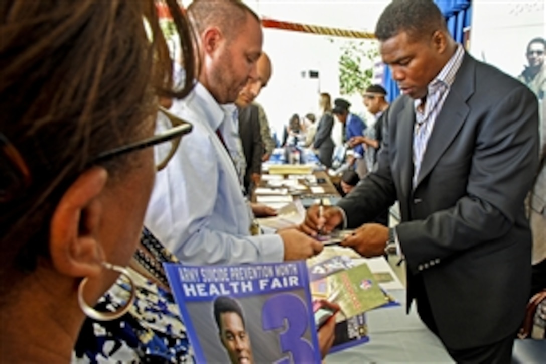 Herschel Walker, Dallas Cowboy legend and 1982 Heisman Trophy winner, opens the Army Suicide Prevention Month Health Fair in the Pentagon courtyard, Sept. 12, 2012, by penning autographs on posters, photos, magazines and replica helmets.