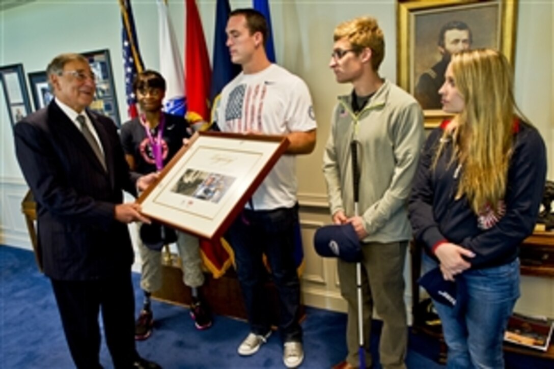 Defense Secretary Leon E. Panetta accepts a gift from U.S. Paralympic Team members Kari Miller, Jeremy Campbell, Brad Snyder and Cortney Jordan during a visit to the Pentagon, Sept. 13, 2012.
