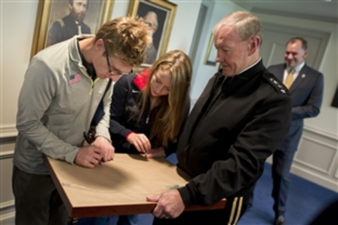 U.S. Paralympic Team members Brad Snyder and Cortney Jordan autograph the back of a gift presented to Army Gen. Martin E. Dempsey, chairman of the Joint Chiefs of Staff, during a visit by the athletes to the Pentagon, Sept. 13, 2012.