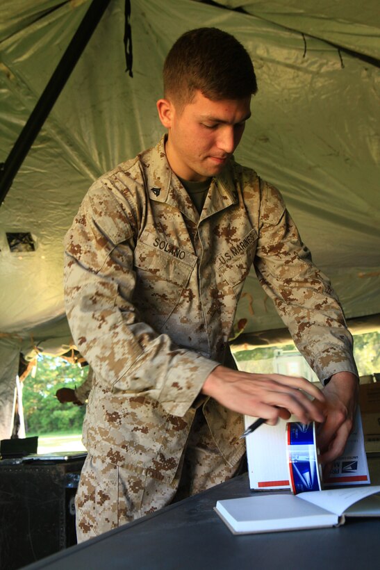 Cpl. Timothy Solano, a combat correspondent with the 2nd Marine Division, packages an article of mail inside a field-expedient post office aboard Camp Lejeune, N.C, Sept. 11, 2012. Marines from Combat Logistics Regiment 2, 2nd Marine Logistics Group processed mail for patrons such as Solano during a training exercise preparing them to perform postal missions in isolated environments. 
