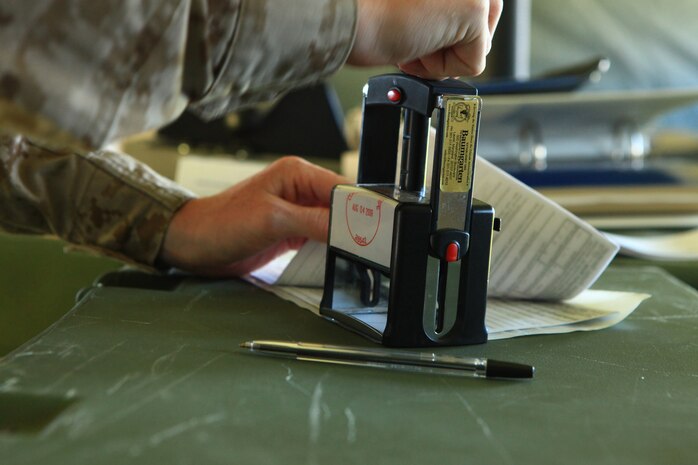 A postal clerk with Combat Logistics Regiment 2, 2nd Marine Logistics Group stamps paperwork required to mail packages overseas during a training exercise aboard Camp Lejeune, N.C., Sept. 11, 2012. A team of 14 postal Marines preparing for deployment processed mail for patrons in a field-expedient post office set up outside the base’s main post office. 