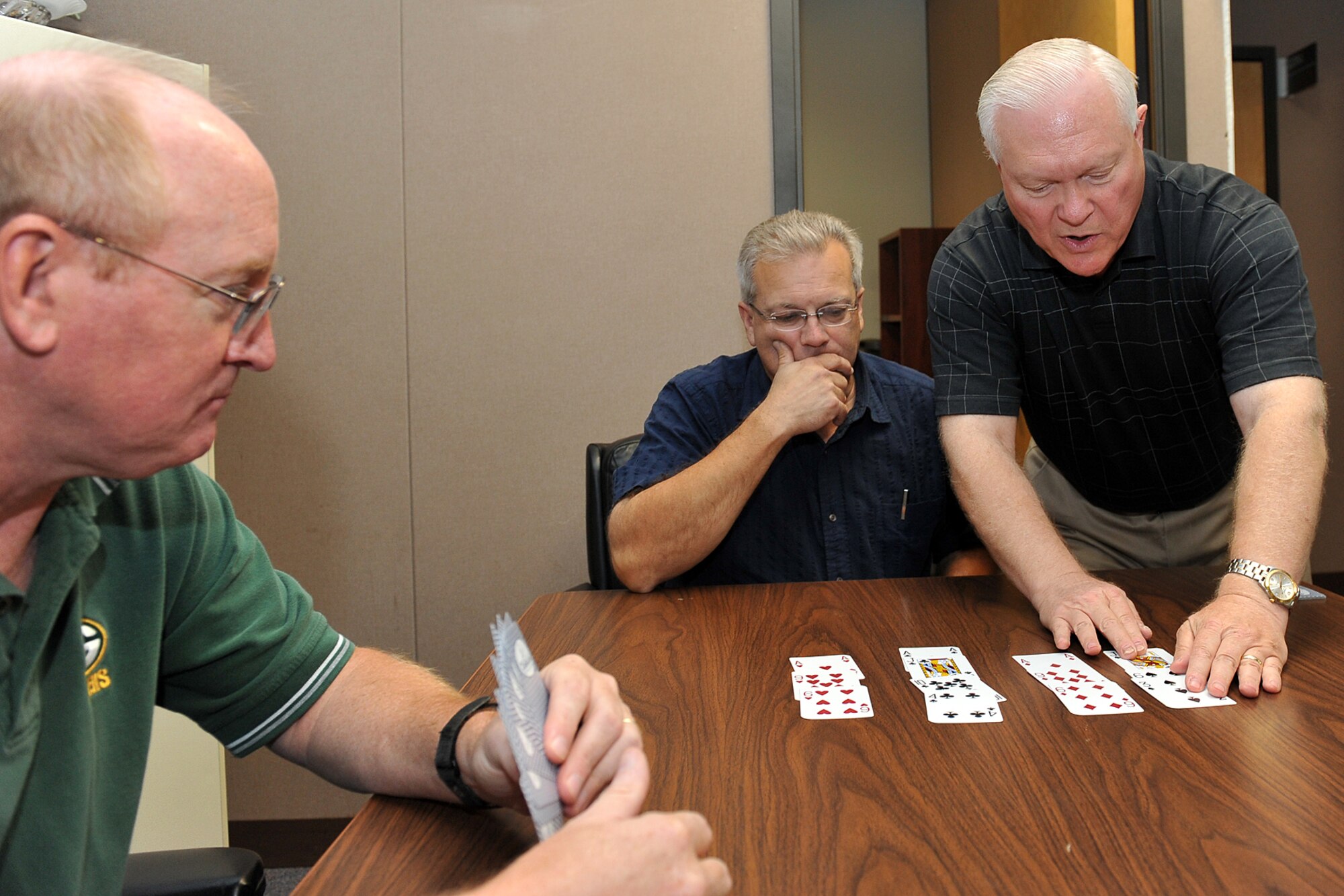 U.S. Air Force civilian Bruce Tway observes U.S. Air Force civilian Mike Slater become the “dummy” while U.S. Air Force civilian Pierre Flatowicz, all with the 55th Force Support Squadron, instructs them about the rules of bridge inside Building C on Offutt Air Force Base, Neb., Sept. 13. (U.S. Air Force photo by Charles Haymond/Released)