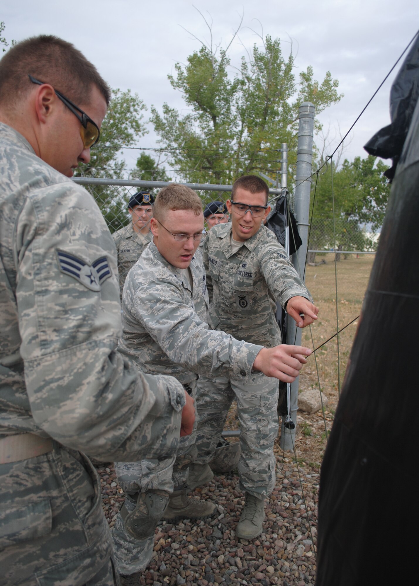 1st Lt. Michael Bruton, 341st Security Forces Group Tactical Response Force officer in charge, center, communicates to Senior Airman Collin Kleckley, 341st Security Forces Squadron member, left, and Senior Airman Anthony Trujillo, 741st Missile Security Forces Squadron member, right, on how to move through an opening in the wire during a mental challenge at the Warrior Launch Facility. The Global Strike Challenge security forces team members were tasked with going through an opening in the fence without touching the wire or verbally communicating. (U.S. Air Force photo/Airman 1st Class Katrina Heikkinen)