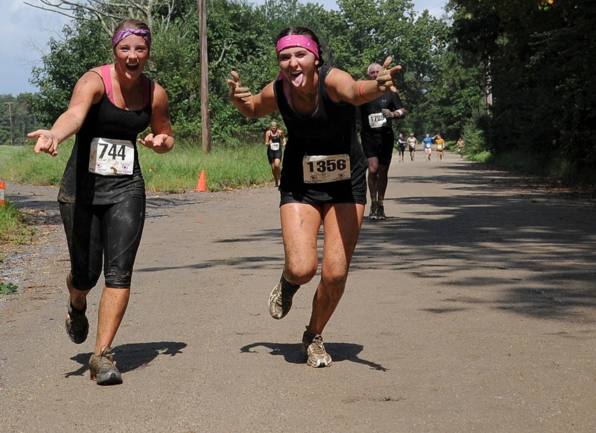 Two participants smile for the camera as they run toward the next set of obstacles Sept. 8 at Joint Base McGuire-Dix-Lakehurst's "Beast of the East" Mud Run here. The two runners were on their way to the "Be All You Can Be Confidence Course" in which they would climb monkey bars, balance on rolling logs and scale walls before running to the next obstacle. (U.S. Air Force photo by 2nd Lt. Alexis McGee/Released)