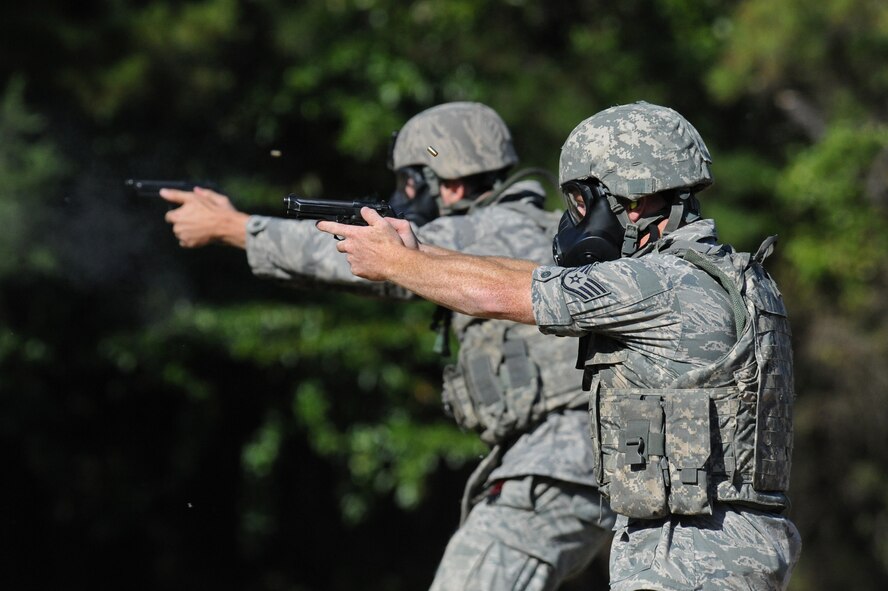 Staff Sgt. Jamie Farmer and Airman 1st Class Cody Rothery, 2nd Security Forces Squadron, shoot at targets with M-9 pistols at the Bossier Parish Sheriff?s Office pistol range in Plain Dealing, La., Sept. 11. The Airmen donned their gas masks to participate in a head-to-head shoot off, to prepare them for the 2012 annual Global Strike Challenge. In the head-to-head shoot off the Airmen had to draw their weapon and shoot their target before their opponent. The shooters had to do 10 push-ups for missed targets and another 10 for losing the shoot-off. (U.S. Air Force photo/Senior Airman Micaiah Anthony)(RELEASED)