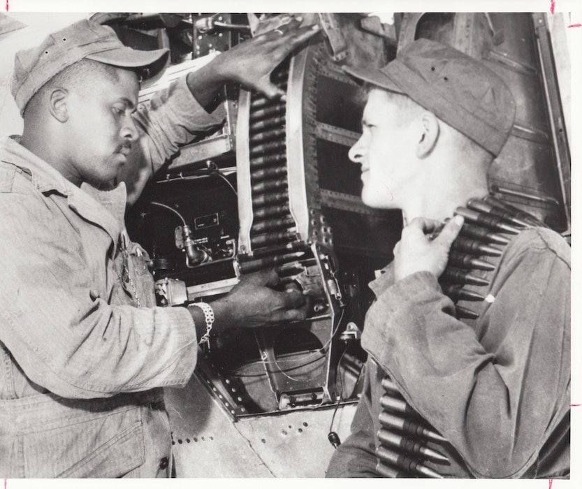 Airman First Class Joseph Godde (left) and Airman Donald Richmond of the 113th Fighter Interceptor Squadron, Indiana Air National Guard, load the .50-caliber machine guns of an F-80 during annual training in 1955.