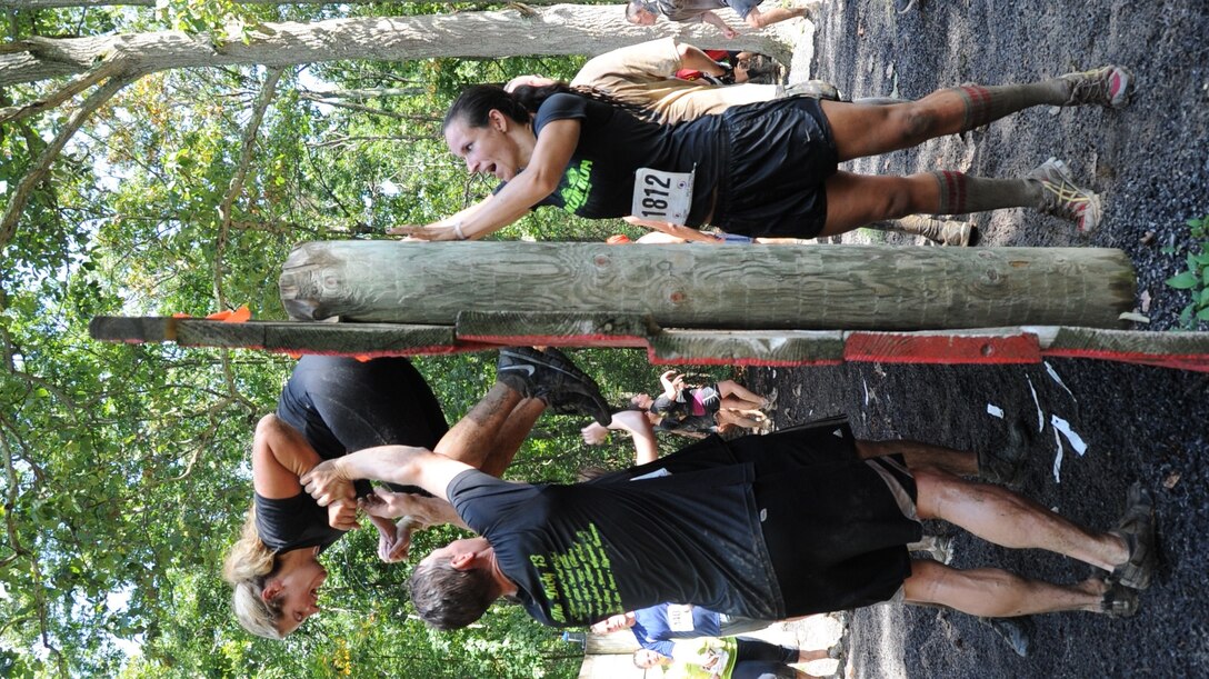 Participants help each other climb over a wall Sept. 8 during the “Be All You Can Be” obstacle course at the Joint Base McGuire-Dix-Lakehurst ‘Beast of the East’ Mud Run. The event was much more than a run for the 2,500 runners who raced through JB MDL and braved 23 obstacles. (U.S. Air Force photo by 2nd Lt. Alexis McGee/Released)