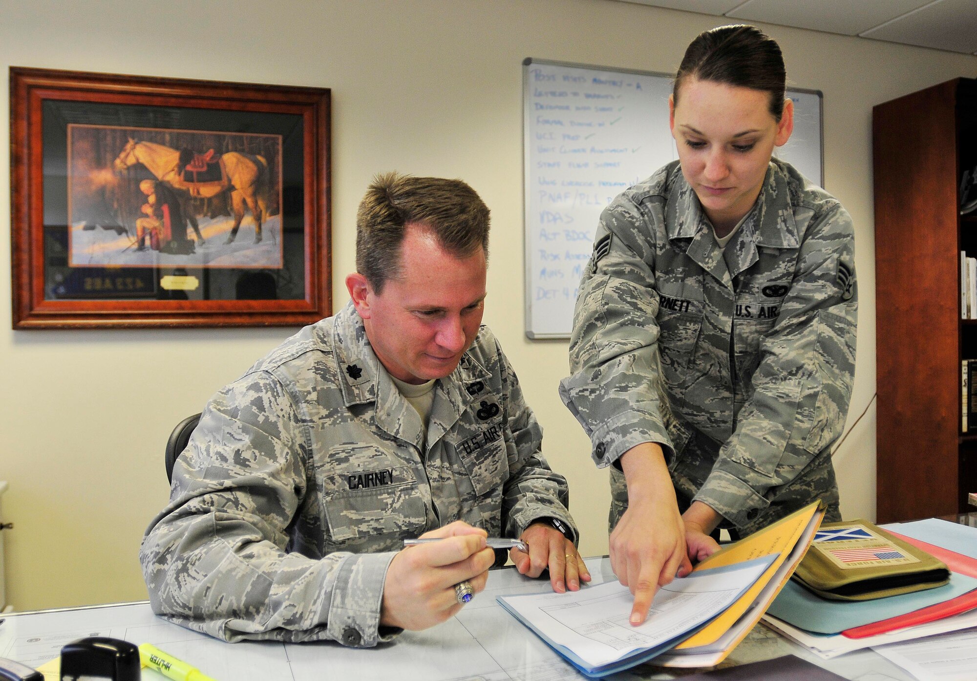 ROYAL AIR FORCE LAKENHEATH, England - Senior Airman Leah Bernett, 48th Security Forces Squadron commander's assistant(right), shows Lt. Col. Paul Cairney, 48th SFS commander, where to sign in his office Sept. 12, 2012. Bernett was nominated for a Liberty Spotlight because she displays the core value of "Excellence in All We Do." (U.S. Air Force photo by Senior Airman Tiffany M. Grigg)