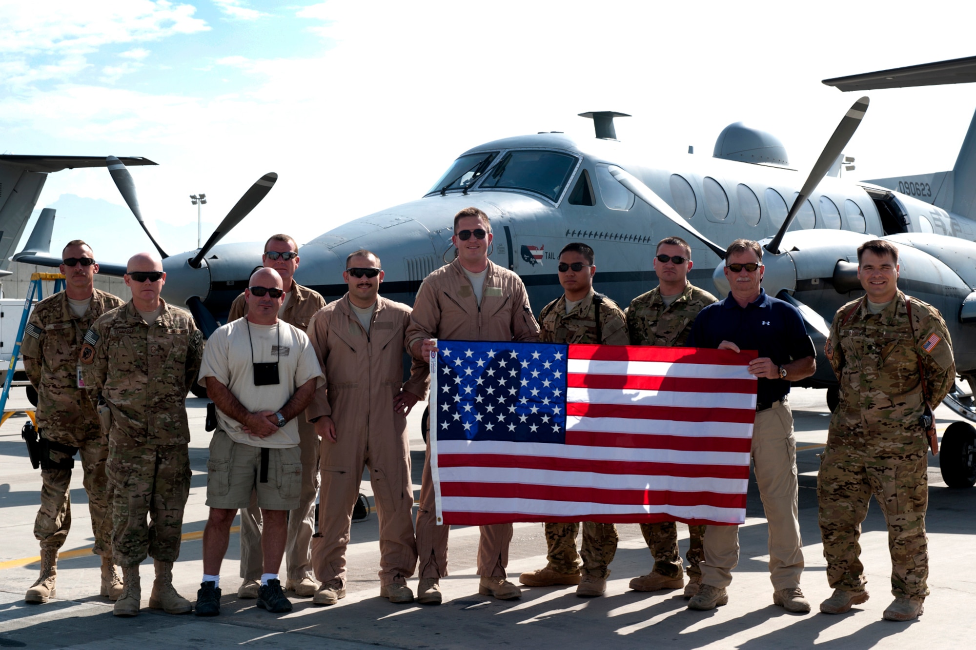 MC-12 Liberty crew members and leadership from the 4th Expeditionary Reconnaissance Squadron pause for a photo in front of one of their aircraft at Bagram Airfield, Afghanistan, September 11, 2012. The conclusion of this mission marks a milestone, as it signifies the 4 ERS officially exceeding over 100,000 flying hours using the MC-12s since the unit was stood up in Dec. 2009. 100,000 flying hours roughly equates to 11 and a-half years of flying for one the aircraft. 4 ERS leadership can say they accomplished this feat in under three years using its fleet of MC-12s. The flag in the photo was flown on the first 4 ERS combat mission at Bagram. (U.S. Air Force photo/1st Lt. Marlene Solano)