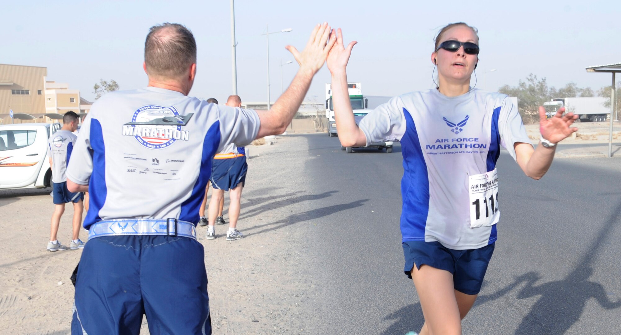 SOUTHWEST ASIA – A member of the 386th Air Expeditionary Wing high-fives a fellow runner as she crosses the finish line completing 13.1 miles for a half-marathon during the deployed Air Force Marathon here Sept. 15. Deployed members were able to participate in a 10K or half-marathon. (U.S. Air Force photo/Staff Sgt. Alexandra M. Boutte)