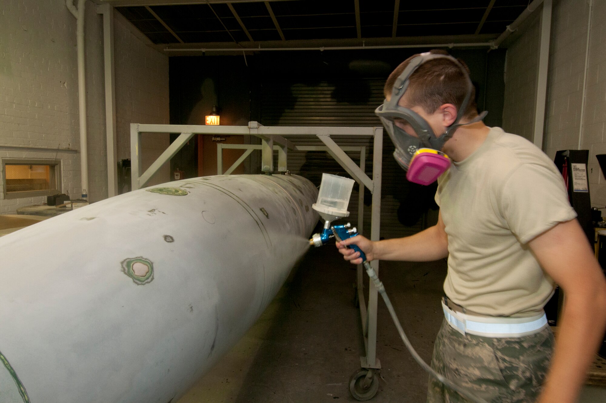 Airman 1st Class Mitchell Groh demonstrates the technique used to paint a centerline tank while working in the painting bay of the 127th Maintenance Squadron at Selfridge Air National Guard Base, Mich., Sept. 15, 2012. In this instance, Groh is using water in his spray gun to simulate the application of paint, due to the presence of the photographer in the painting area. While maintenance Airmen at the base said the paint on an aircraft plays a major role in corrosion control and has other benefits, they also take a great deal of pride in the appearance of the aircraft they maintain.  The centerline tank is used by A-10 Thunderbolt II aircraft assigned to the base as an additional, external fuel tank when the aircraft must make long treks, such as a trip overseas. (Air National Guard photo by TSgt. Robert Hanet)