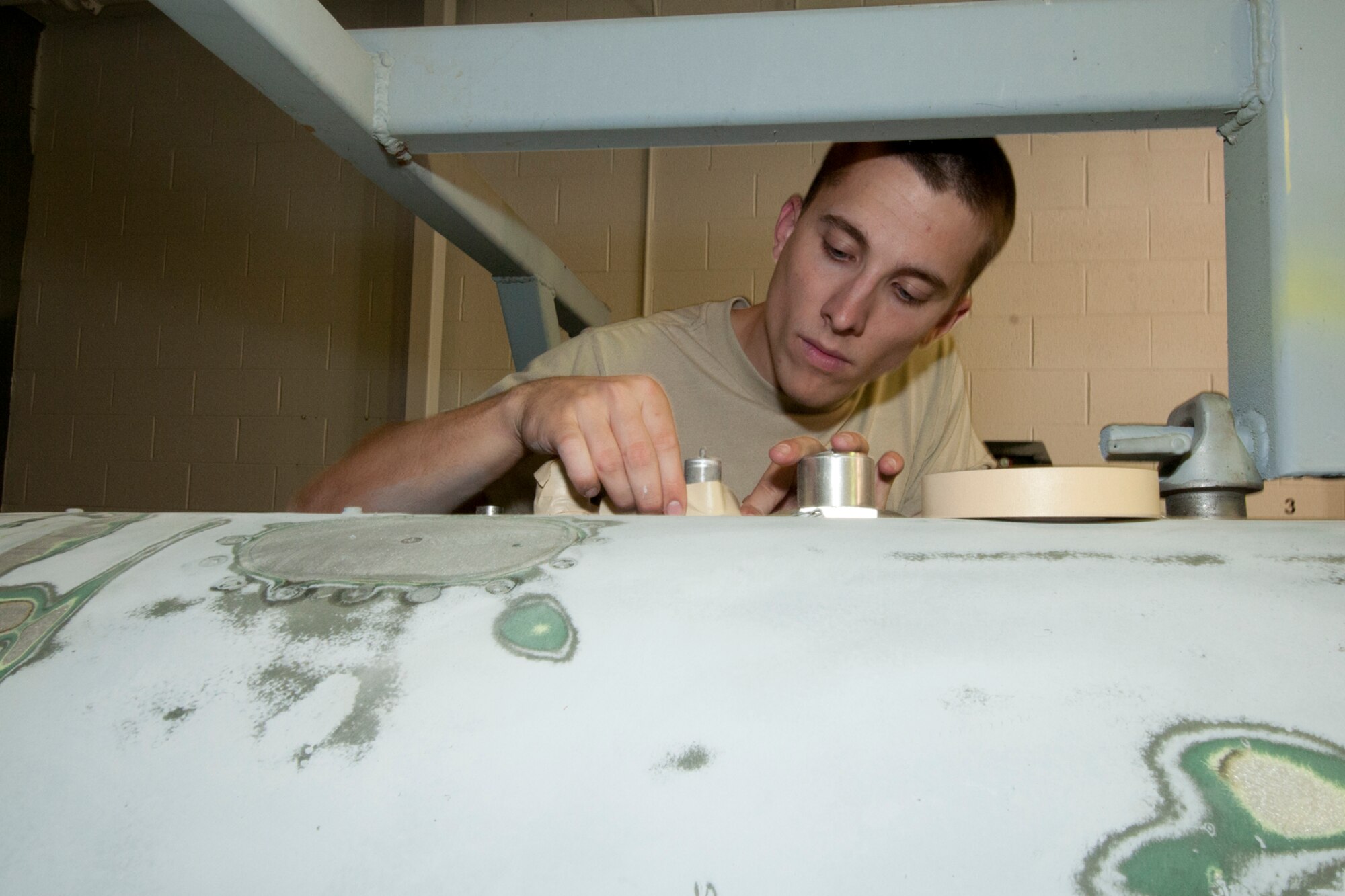 Airman 1st Class Mitchell Groh tapes off a part of a centerline tank that must remain paint-free as part of the preparation work for painting the tank while working in the painting bay of the 127th Maintenance Squadron at Selfridge Air National Guard Base, Mich., Sept. 15, 2012. While maintenance Airmen at the base said the paint on an aircraft plays a major role in corrosion control and has other benefits, they also take a great deal of pride in the appearance of the aircraft they maintain.  The centerline tank is used by A-10 Thunderbolt II aircraft assigned to the base as an additional, external fuel tank when the aircraft must make long treks, such as a trip overseas. (Air National Guard photo by TSgt. Robert Hanet)