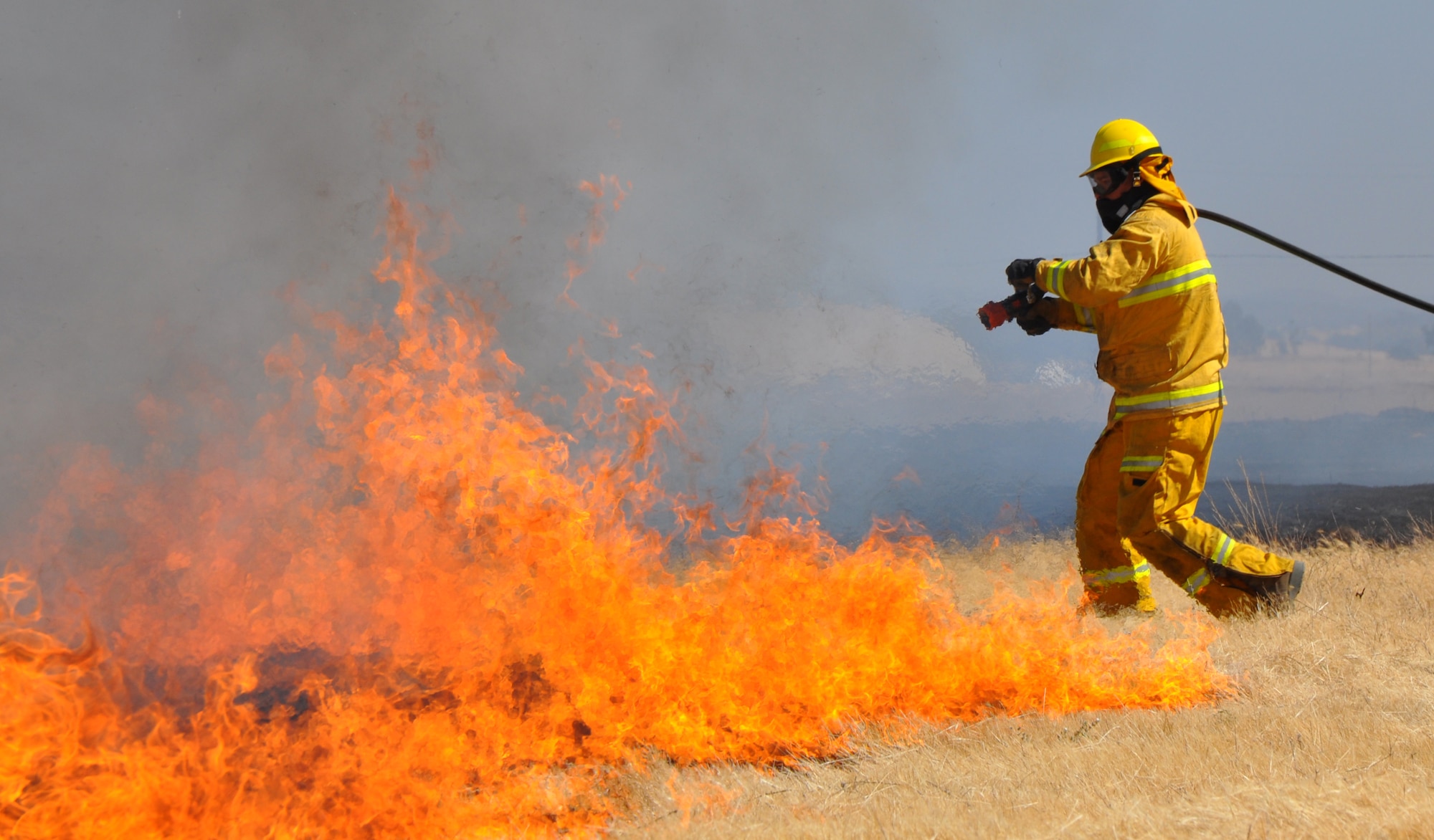 A U.S. Air Force firefighter battles a grass fire at Beale Air Force Base, Calif., Sept. 13, 2012. Beale firefighters often support local fire departments during the fire season. (U.S. Air Force photo by Staff Sgt. Robert M. Trujillo/Released)