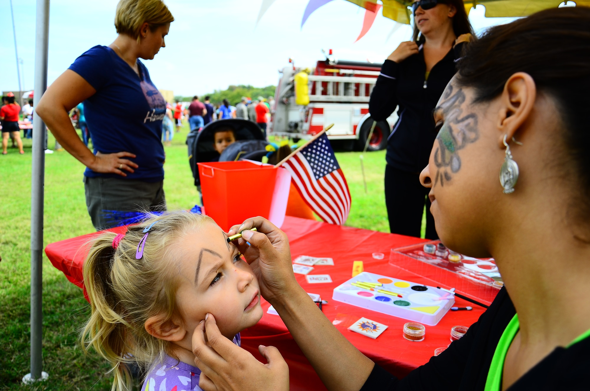 A little girl gets her face painted like a cat by a member from the 69th Aerial Port Squadron the Sports and Family Day event Day near the West Fitness Center, Sept.16, 2012. This was the Fourth Annual 459 Air Refueling Wing Family Day and the first time incorporating sports into the event. The 459th Maintenance Group took home the trophy.  (U.S. Air Force photo/ Senior Airman Chris Friday)