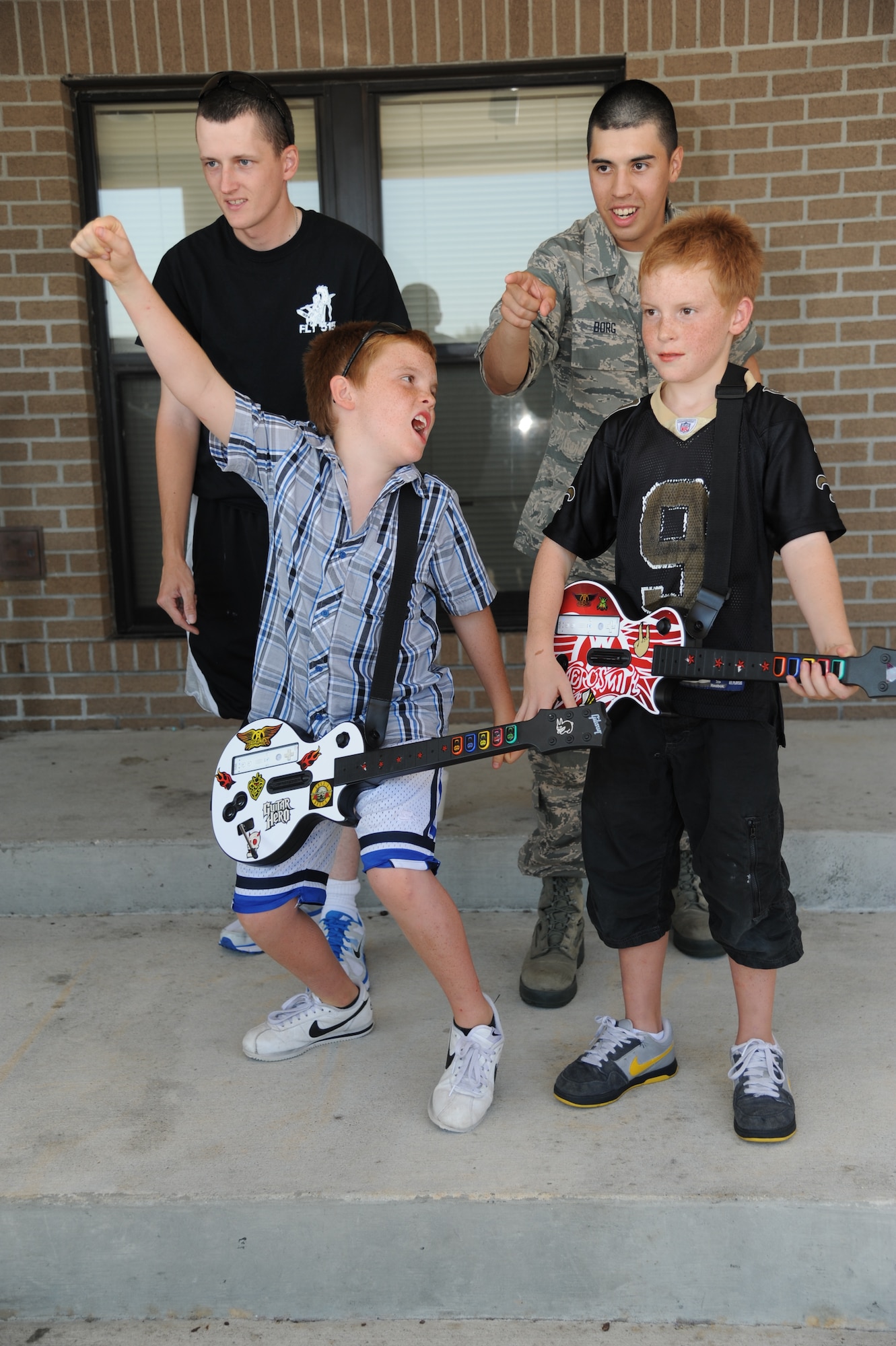 Eleven-year-old twins, Logan and Tyler Walters, play guitar hero as Airman Joseph Greninger, 336th Training Squadron and Airman 1st Class Anthony Borg, 334th TRS, cheer them on at the 65th Air Force Birthday Celebration event at the Triangle Sept. 14, 2012, at Keesler Air Force Base, Miss. The event featured live music, food, beverages, games, contests and prizes.  (U.S. Air Force photo by Kemberly Groue)