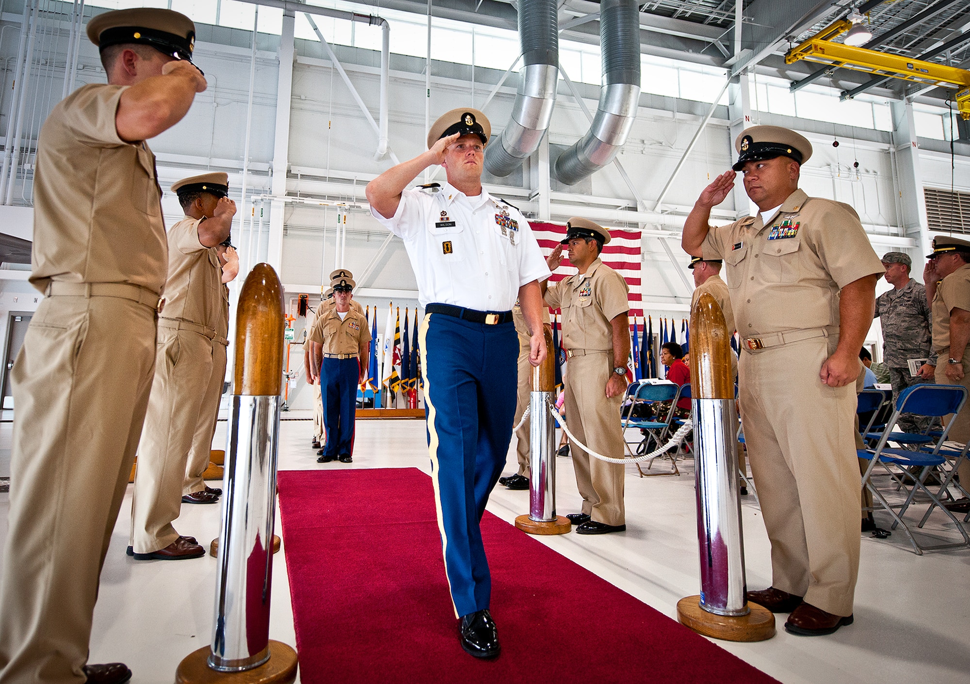 Sgt. 1st Class Todd Wilson, an instructor at Naval School, Explosive Ordnance Disposal, salutes as he walks past the posted sideboys during the chief petty officer pinning ceremony held by the Navy's F-35 Lightning II squadron, VFA-101, Sept. 14 at Eglin Air Force Base, Fla.  Wilson and a Marine EOD instructor volunteered to participate in the chiefs’ induction process and ceremony to become honorary chief petty officers. There were four Sailors who pinned on the new rank.  (U.S. Air Force photo/Samuel King Jr.)