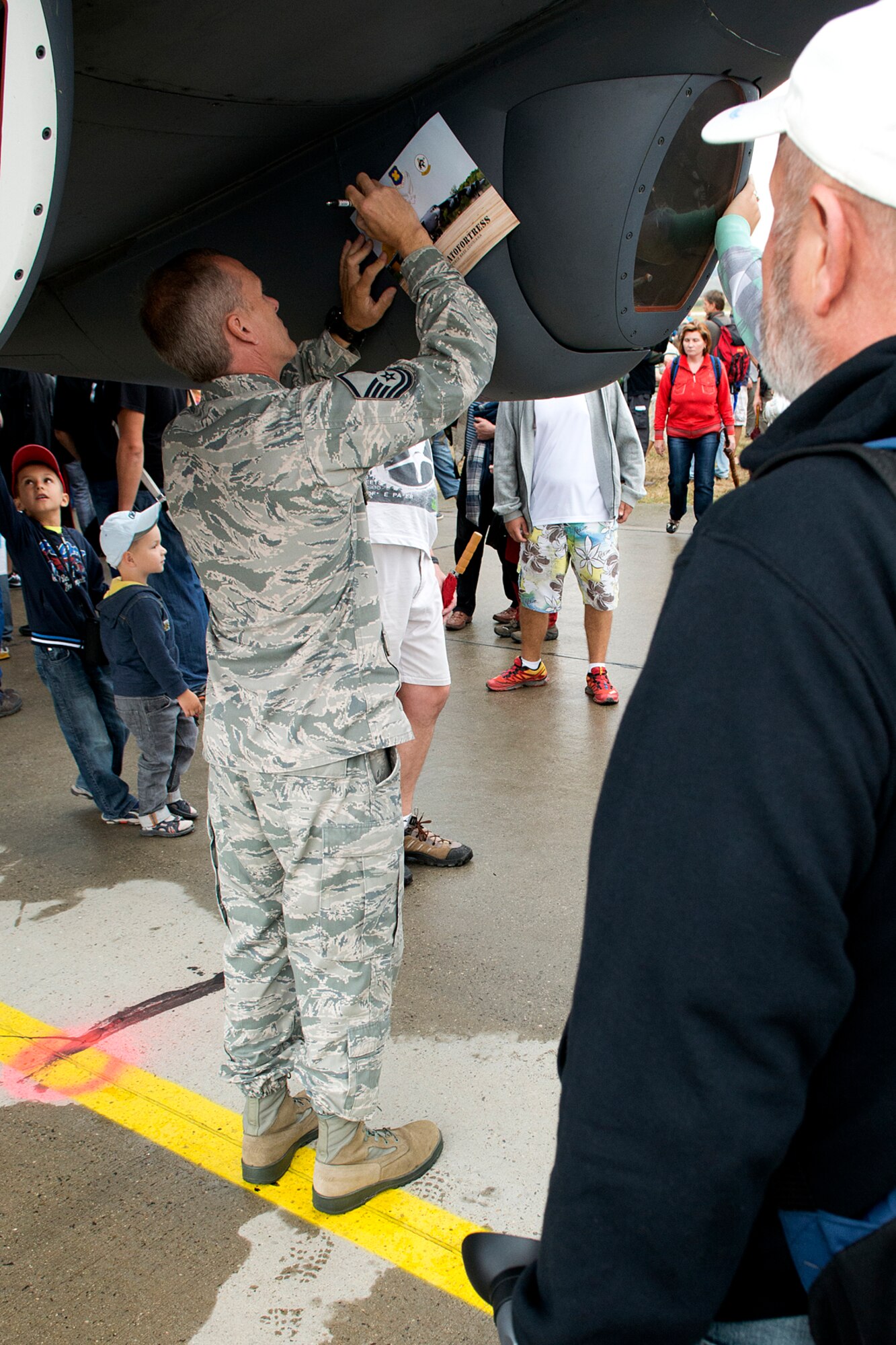 U.S. Air Force Master Sgt. Robbie Turcotte, 307th Aircraft Maintenance Squadron flight line expeditor, signs a B-52 fact sheet for a spectator during the Slovak International Air Fest, Sept. 1, 2012, Sliac, Slovakia. The SIAF is the largest air show in Slovakia with aerial demonstrations and displays from aircraft throughout Europe and Asia. (U.S. Air Force photo by Master Sgt. Greg Steele/Released)