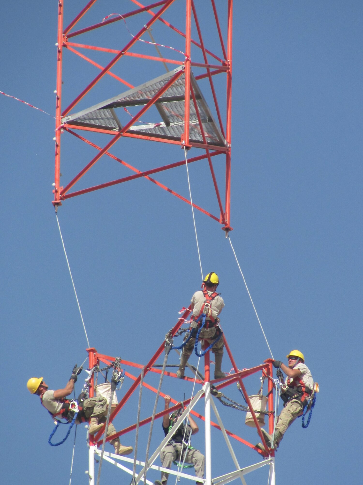 Members of 455th Expeditionary Communications Squadron prepare to connect tower sections while a civilian contractor helicopter lowers sections into place. A specialized team from several Air National Guard Engineering Installation Squadrons deployed to Bagram Airfield, Afghanistan, combined their efforts to built and setup the 170-foot communications tower, greatly increasing radio communication range. (U.S. Air Force photo/1Lt. Bruce Champion)