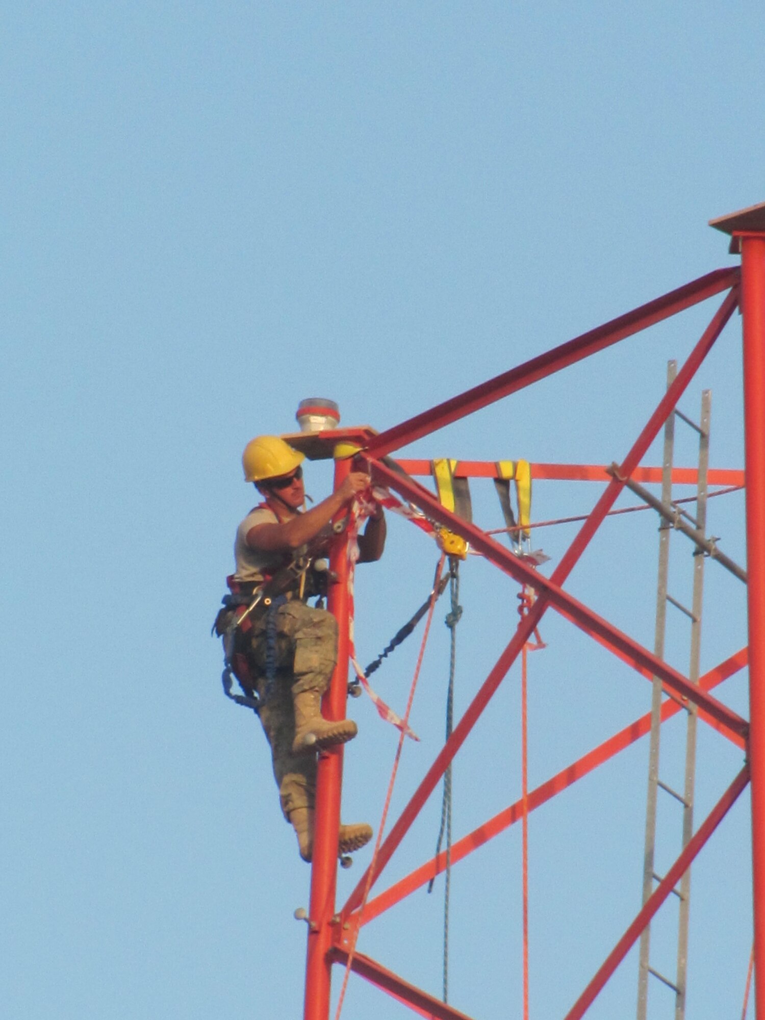 Members of 455th Expeditionary Communications Squadron prepare to connect tower sections when a civilian contractor helicopter lowers sections into place. A specialized team from several Air National Guard Engineering Installation Squadrons deployed to Bagram Airfield, Afghanistan, combined their efforts to built and setup the 170-foot communications tower, greatly increasing radio communication range. (U.S. Air Force photo/1Lt. Bruce Champion)