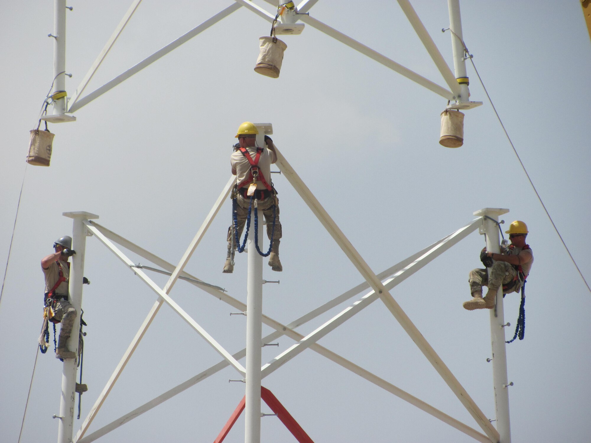 Members of 455th Expeditionary Communications Squadron prepare to connect tower sections when a civilian contractor helicopter lowers sections into place. A specialized team from several Air National Guard Engineering Installation Squadrons deployed to Bagram Airfield, Afghanistan, combined their efforts to built and setup the 170-foot communications tower, greatly increasing radio communication range. (U.S. Air Force photo/1Lt. Bruce Champion)