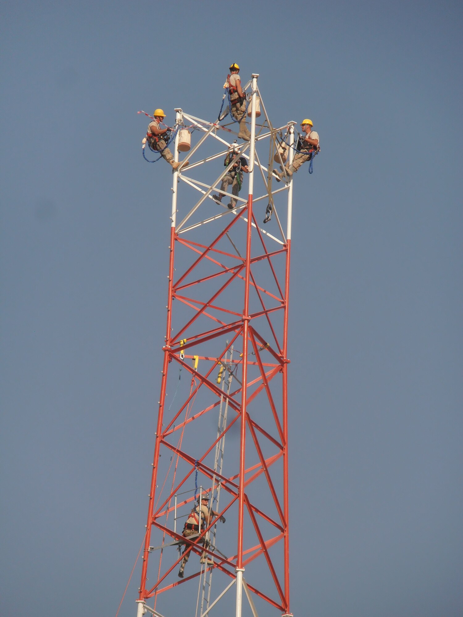 Members of 455th Expeditionary Communications Squadron prepare to connect tower sections when a civilian contractor helicopter lowers sections into place. A specialized team from several Air National Guard Engineering Installation Squadrons deployed to Bagram Airfield, Afghanistan, combined their efforts to built and setup the 170-foot communications tower, greatly increasing radio communication range. (U.S. Air Force photo/1Lt. Bruce Champion)