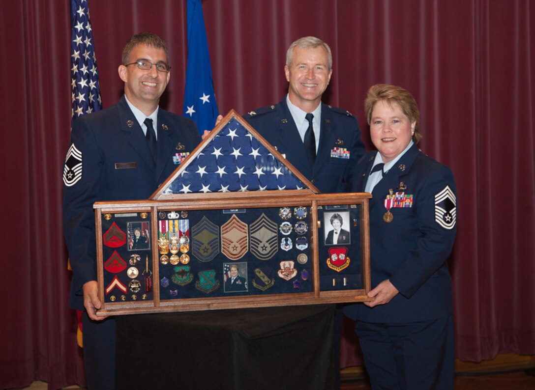 (From left to right) The U.S. Air Force Band Manager Chief Master Sgt. Craig LeDoux, the Band's commander and conductor, Col. Larry H. Lang present Chief Master Sgt. Barbara Taylor with a shadow box representing her 30-year military career. (Photo by retired Air Force Senior Master Sgt. Rob Mesite)