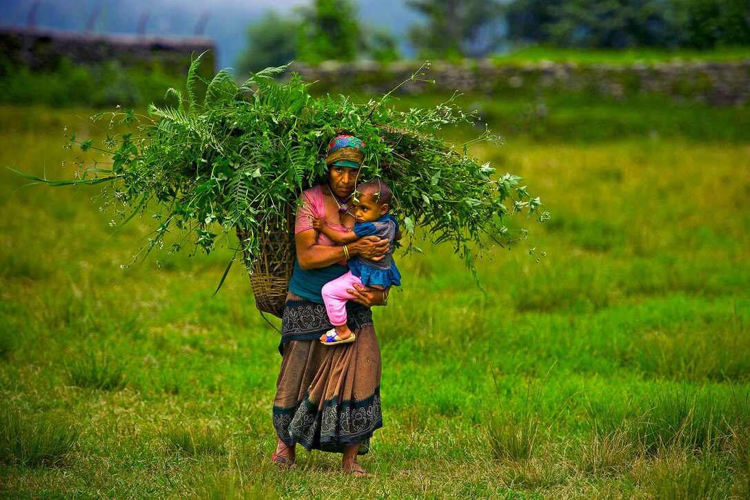 A Nepalese woman carries a child across a field in the Dhikur Pokhari Village Development Committee, Kaski district, Nepal, Sept. 11, 2012, during Pacific Angel 12-4.