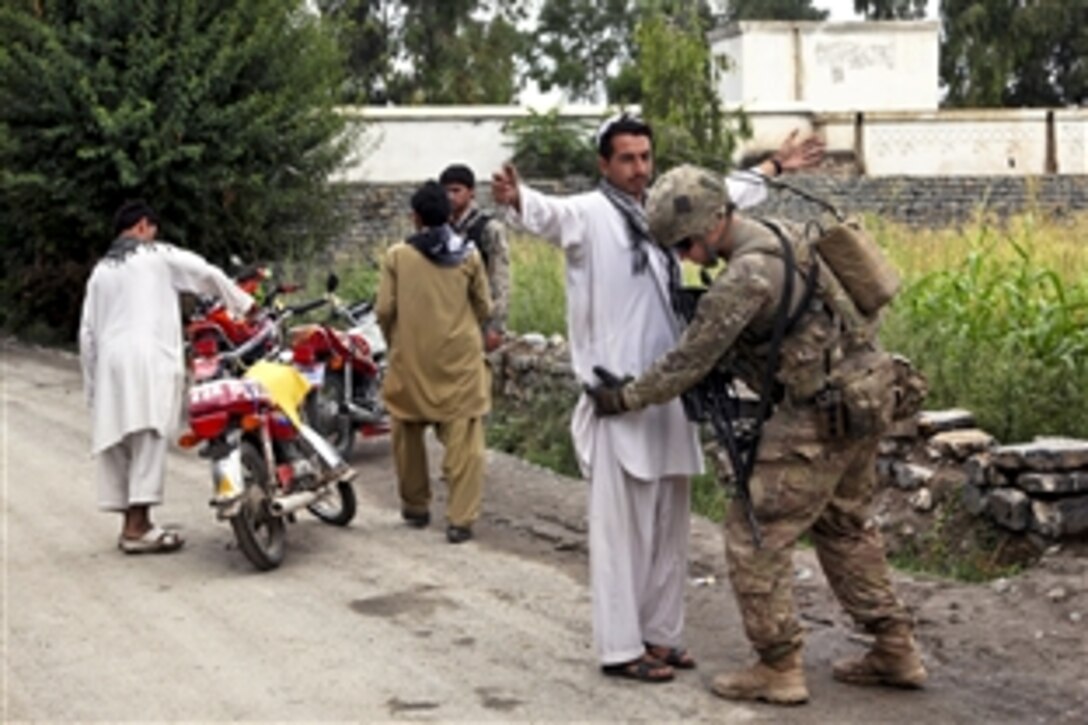 A U.S. soldier checks an Afghan man for weapons before allowing him through a security checkpoint in Ayub Khe in, Afghanistan's Khost province, Sept. 8, 2012.