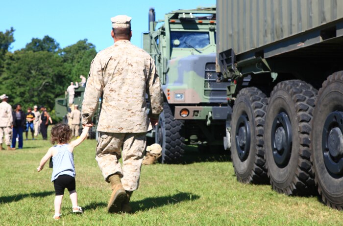 A Marine and his child walk the length of a mock seven-vehicle convoy during the Jane Wayne Day activities for Combat Logistics Battalion 6, 2nd Marine Logistics Group aboard Camp Lejeune, N.C., Sept. 12, 2012. The unit left the doors to their vehicles open so spouses and family members could explore the inner workings of the equipment used by the Marines. 