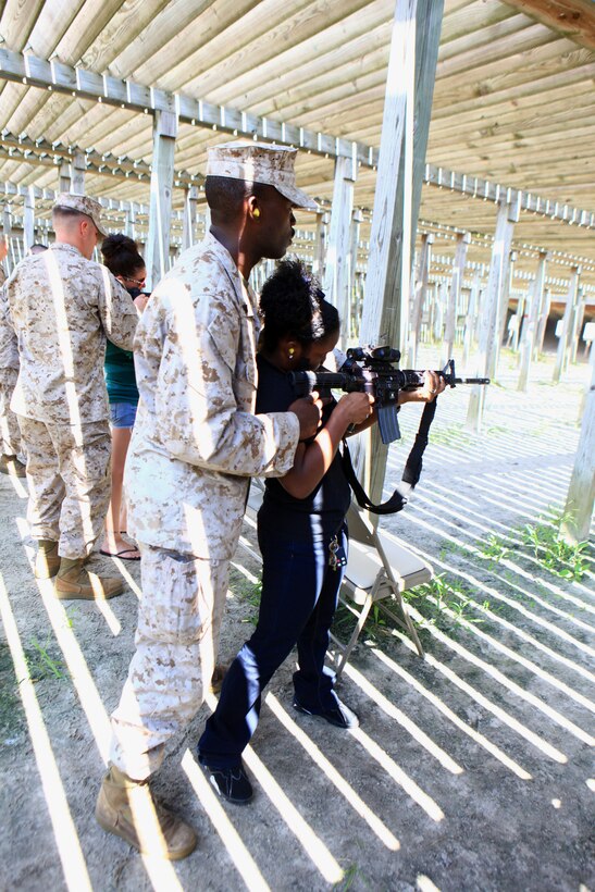 Cpl. Magnus Nnolim, a motor vehicle mechanic with Combat Logistics Battalion 6, 2nd Marine Logistics Group, watches over his wife, Ashdale Nnolim, as she prepares to fire an M-4 carbine during the unit’s Jane Wayne Day activities aboard Camp Lejeune, N.C., Sept. 12, 2012. The live-fire exercise was the first time many of the spouses and family members fired a weapon and allowed them to better understand the daily demands placed on the servicemembers they help to support.