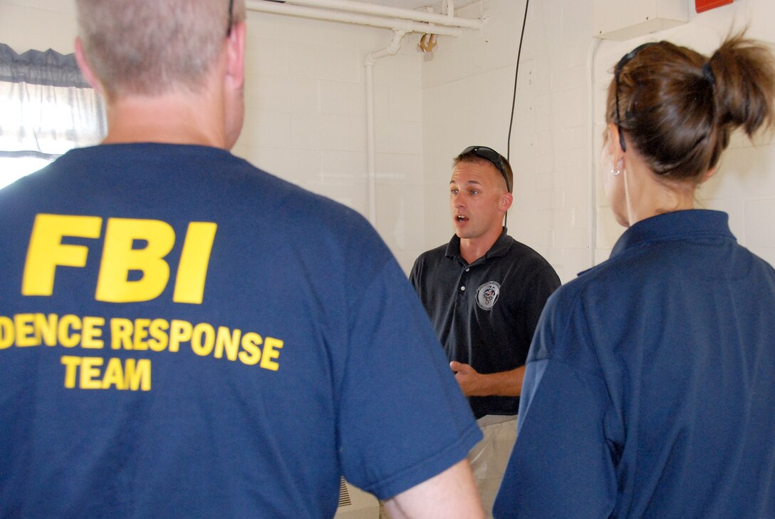 Sgt. Jacob Miller, a survey team member with the Wisconsin National Guard's 54th Civil Support Team, shares information about potentially dangerous chemicals with an FBI Evidence Recovery Team. The training was part of PATRIOT 12, a National Guard domestic response exercise that included both military and civilian agencies. Wisconsin National Guard photo by Sgt. Robert Waight