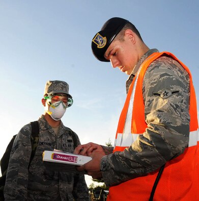 U.S. Air Force Airman Anthony Langone, right, 35th Security Forces Squadron patrolman, performs an identity check on Airman 1st Class Jacques Chevalier, left, 35th Force Support Squadron fitness specialist, during an emergency management exercise at Misawa Air Base, Japan, Sept. 17, 2012. After a simulated explosion on base, EM teams and first responders arrived and began following protocol for the scenario. The 100 percent identification check serves to keep track of everyone in the immediate area. (U.S. Air Force photo by Airman 1st Class Kenna Jackson/Released)