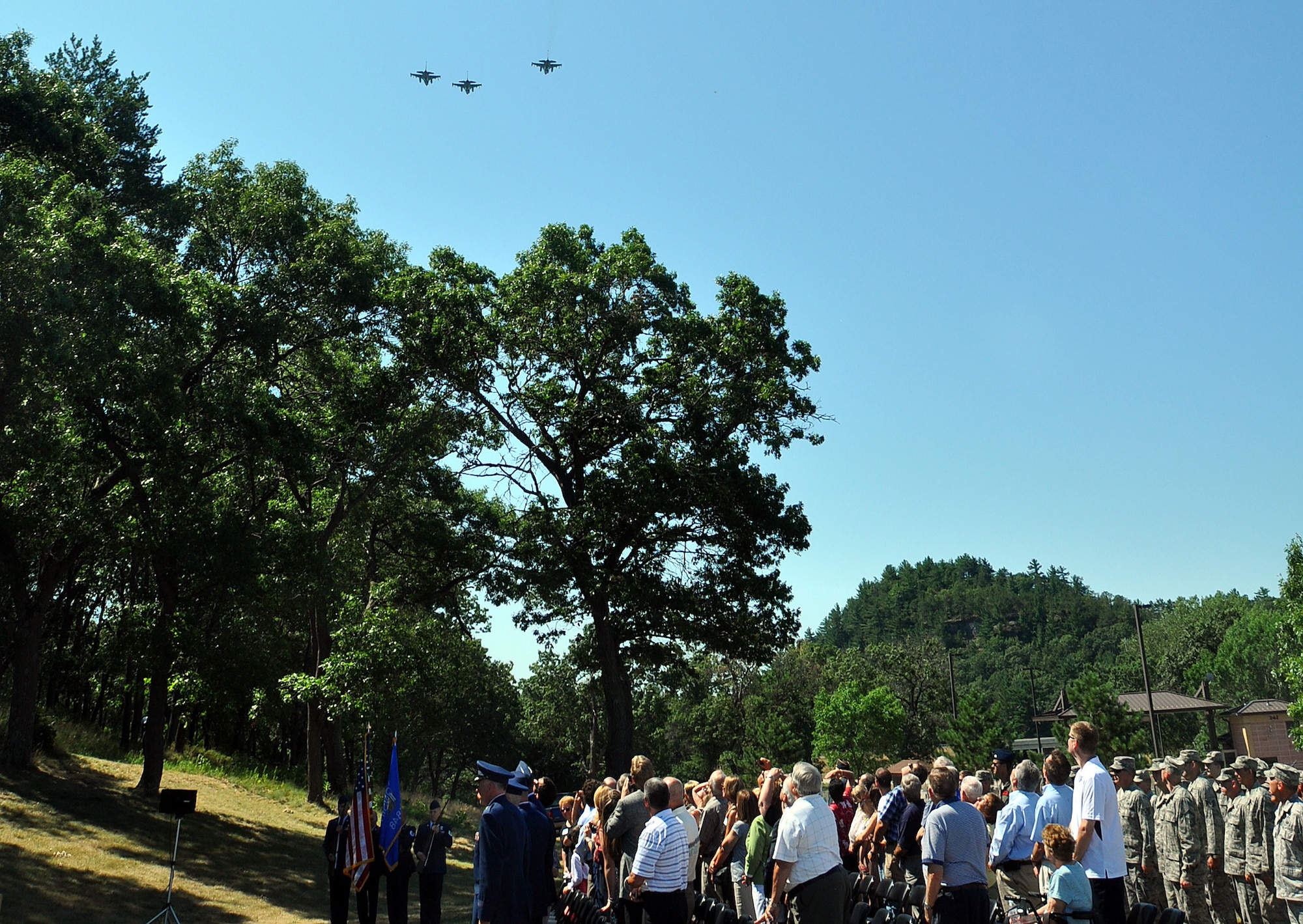 Family members and guests watch a "missing man formation" fly-over at Volk Field during a July 11 memorial service for the base's namesake, 1st Lt. Jerome Volk, the first Wisconsin Air National Guard pilot to die in the line of duty during the Korean conflict. Volk was shot down during a combat sortie against communist forces Nov. 7, 1951, and his remains have never been recovered. In 1957 the Wisconsin legislature renamed the portion of Camp Williams used by the Wisconsin Air National Guard as Volk Field. Don Volk, 1st Lt. Volk's younger brother and next of kin, and dozens of other relatives attended the ceremony, which included full military honors. Wisconsin National Guard photo by 1st Sgt. Vaughn R. Larson