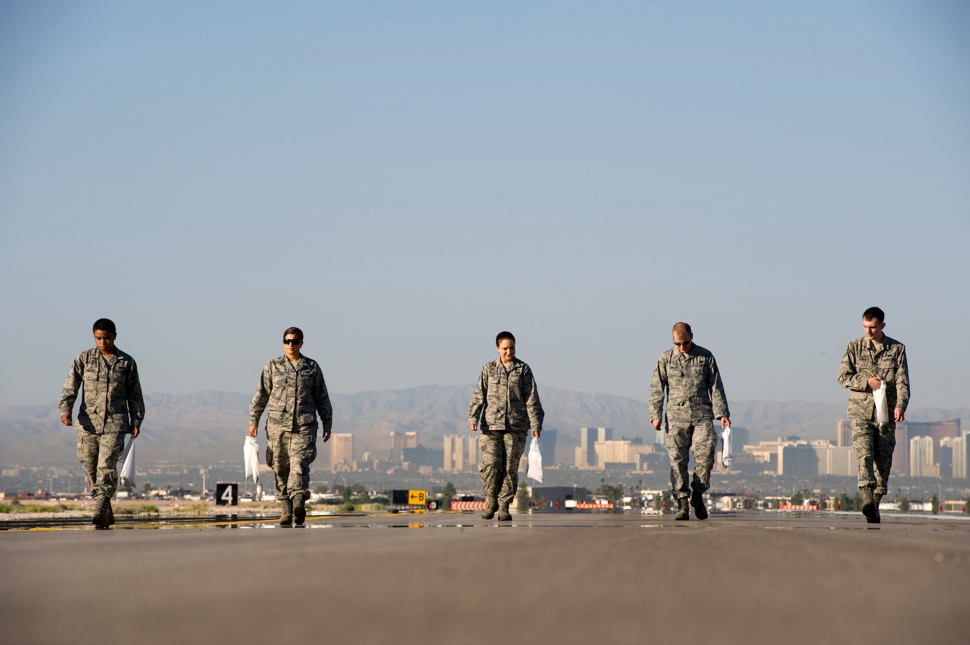 Airmen walk the runway looking for trash during a Foreign Object Debris walk Sept. 14, 2012, at Nellis Air Force Base, Nev. FOD prevention is every individual's responsibility as it can cost millions of dollars of damage to aircraft systems and endanger people. Nellis Airmen conducted the Sept. 14  FOD walk to remove debris that may have gotten onto the airfield from recent construction.(U.S. Air Force photo by Airman 1st Class Christopher Tam)
