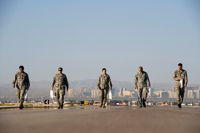 Airmen walk the runway looking for trash during a Foreign Object Debris walk Sept. 14, 2012, at Nellis Air Force Base, Nev. FOD prevention is every individual's responsibility as it can cost millions of dollars of damage to aircraft systems and endanger people. Nellis Airmen conducted the Sept. 14  FOD walk to remove debris that may have gotten onto the airfield from recent construction.(U.S. Air Force photo by Airman 1st Class Christopher Tam)