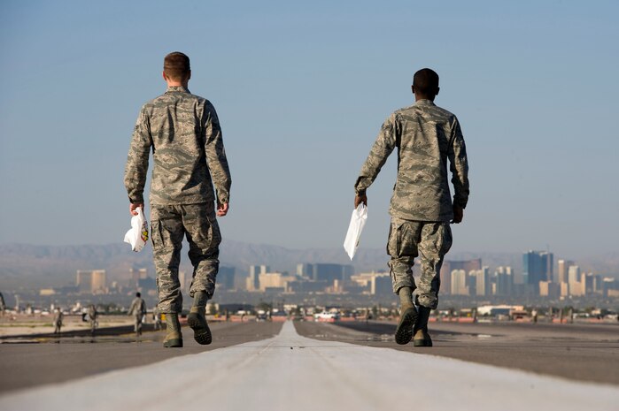 Airman 1st Class Clifton Ford and Airman 1st Class Derek Mobley, 57th Operations Support Squadron air traffic controllers, walk down the runway looking for trash during a Foreign Object Debris walk Sept. 14, 2012, at Nellis Air Force Base, Nev. Seventy-two Airmen and two sweeper trucks participated in the FOD walk which is conducted to ensure the safety of aircraft and Airmen. (U.S. Air Force photo by Airman 1st Class Christopher Tam)