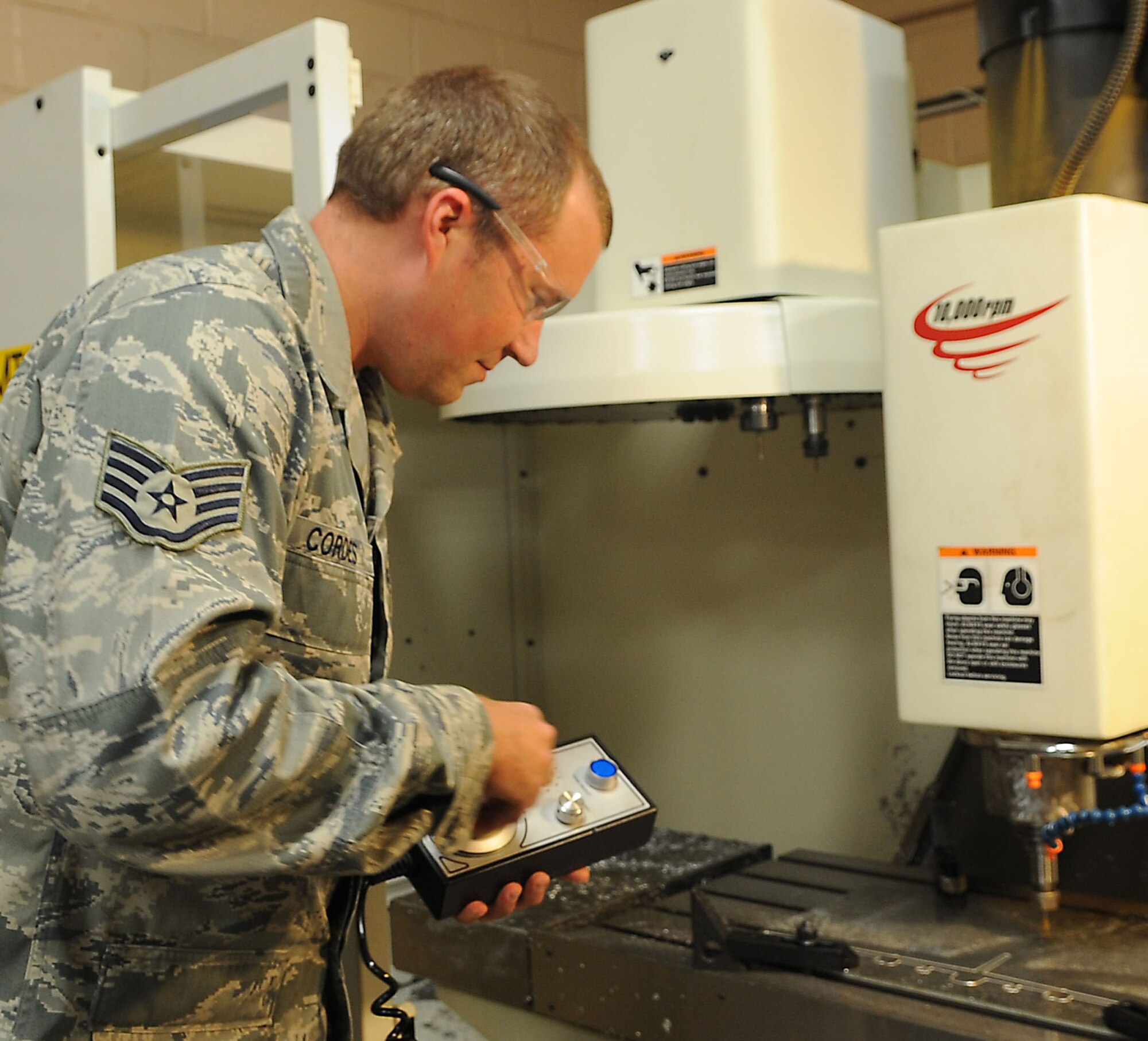 Staff Sgt. David Cordes, 2nd Maintenance Squadron aircraft metals technology craftsman, uses a hand jog to manually move the quill and table on a computer numerical control mill on Barksdale Air Force Base, La., Sept. 18. Although usually automated, the mill can be controlled by hand to create aircraft brackets, test fixtures and anything else need to support the aircraft. (U.S. Air Force photo/Senior Airman Kristin High)(RELEASED)