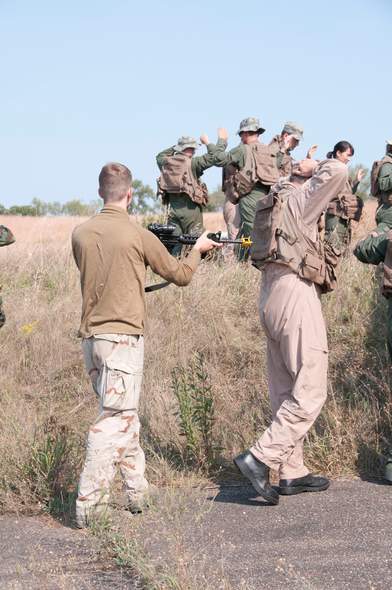 Members of the 133rd Airlift Wing are taking part in survival, evasion, resistance, and escape (SERE) training at the Army Training Site Arden Hills, Minnesota Sept. 16, 2012. An airman of the 133rd Security Forces Squadron role plays the part of enemy captor, as he guides the captured members of the Wing to their holding cells during SERE training. U.S. Air Force photo by Airman 1st Class Kari L. Giles/released