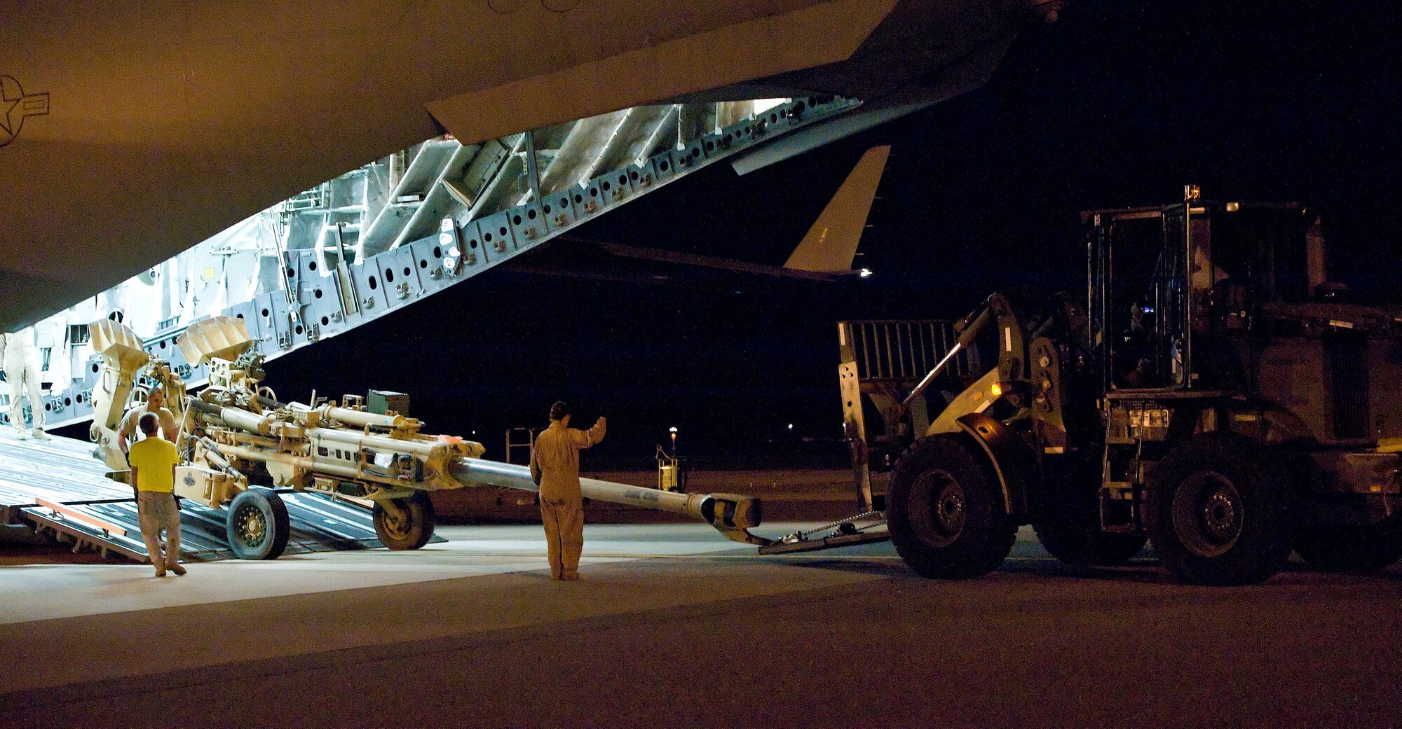 A loadmaster oversees the off-loading of a piece of artillery from a C-17 Globemaster III Sept. 4, 2012, at Dover Air Force Base, Del. Aerial port members and aircrew work side-by-side at all hours of the day to keep cargo moving through Dover AFB. (U.S. Air Force photo by Roland Balik)