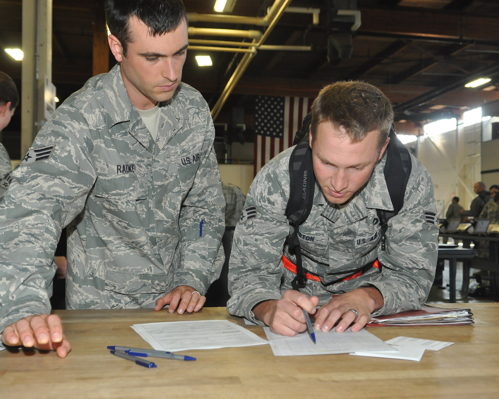 Senior Airman Josiah Barton, 446th Civil Engineer Squadron heating, ventilation and air conditioning technician, fills out finance paperwork with the help of Senior Airman Clay Radke, 446th Airlift Wing financial management specialist, Sept. 13, 2011, upon his return to Joint Base Lewis-McChord, Wash. Barton was one of many Airman to participate in a fly-away operational readiness exercise at Volk Field, Wis. (U.S. Air Force photo/Staff Sgt. Sean Tobin)