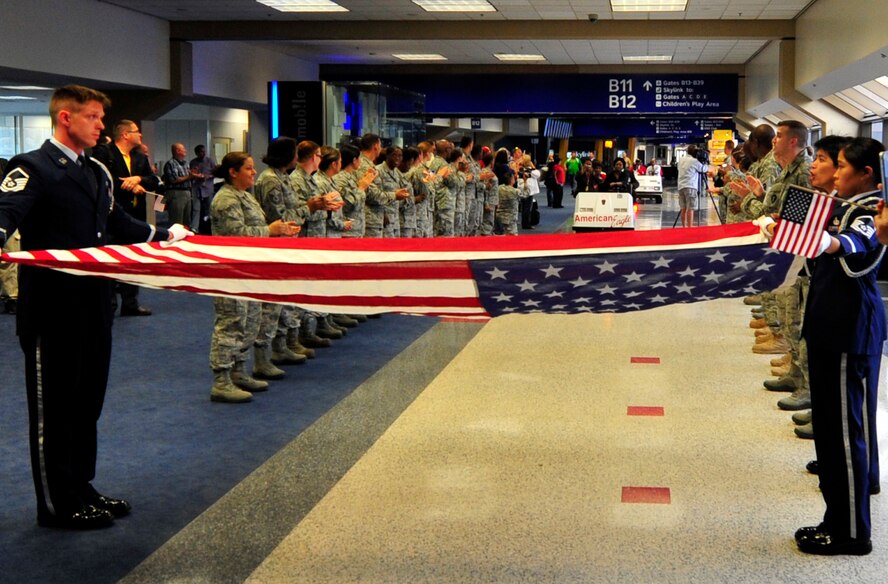 Master Sgts. Todd Ryan and Regina Hudson hold the American flag at table top position to honor four Tuskegee Airmen at DFW airport Sept. 14. Members of the 301st Fighter Wing gathered at DFW airport to form a "path of honor" for the Tuskegee Airmen who were traveling from Dallas to Montgomery, Ala., to attend "An Evening with the Red Tails" event at Tuskegee University. (U.S. Air Force photo/Senior Airman Martha Whipple)