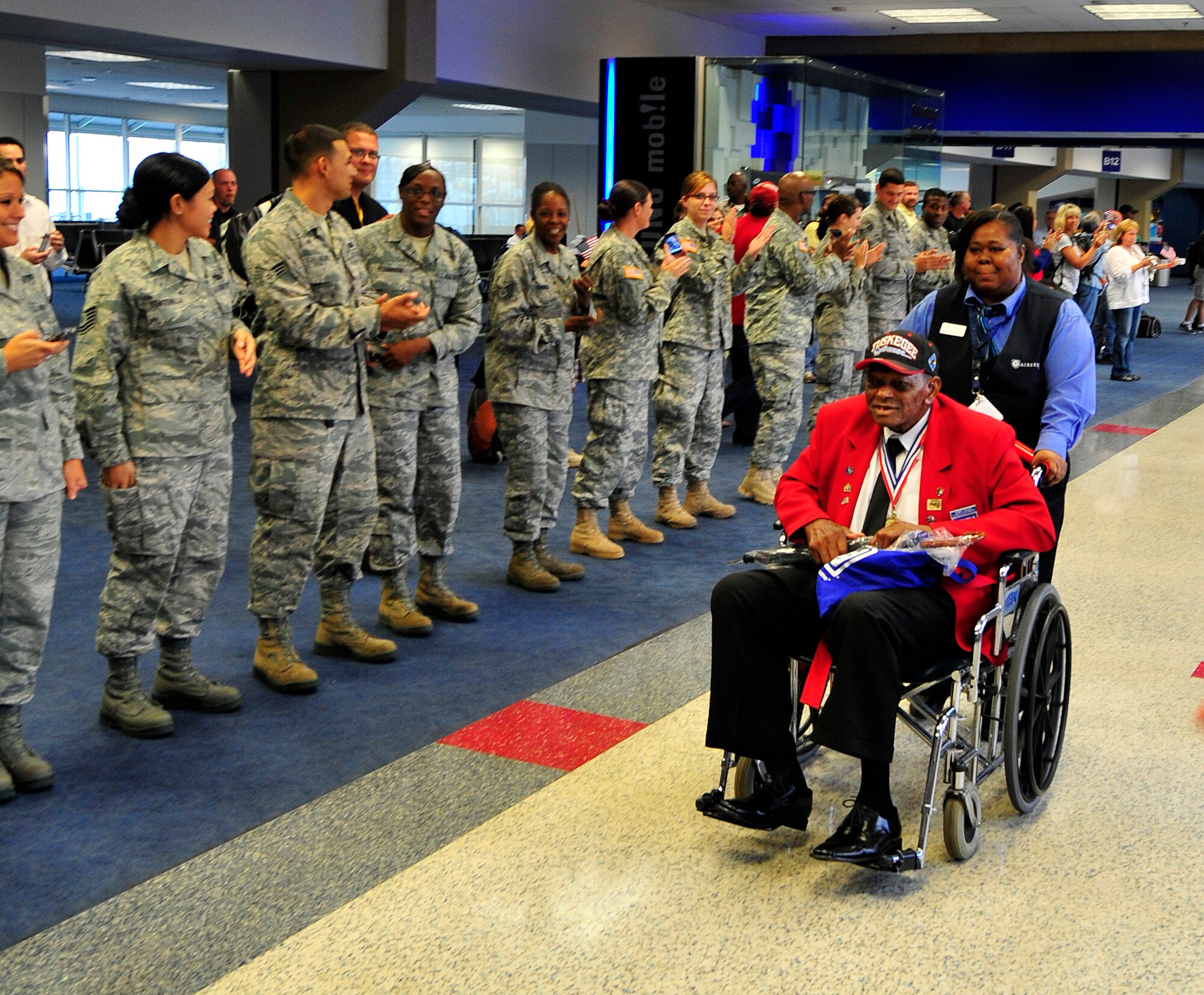 Staff Sgt. Homer Hogues rolls down the “path of honor” at DFW airport Sept. 14. Members of the 301st Fighter Wing gathered at DFW airport to form a "path of honor" for four Tuskegee Airmen who were traveling from Dallas to Montgomery, Ala., to attend "An Evening with the Red Tails" event at Tuskegee University. (U.S. Air Force photo/Senior Airman Martha Whipple)