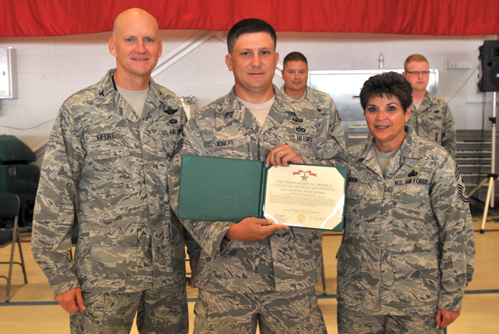 Master Sgt. Raleigh Rogers  (center), stands with 125th Fighter Wing Commander, Col. James Eifert (left) and 125th Fighter Wing Command Chief Master Sgt. Sharon Ervin after Rodgers was awarded the Bronze Star at a ceremony, August 19, 2012, 125th Fighter Wing, Florida Air National Guard, Jacksonville, Fla. Rogers distinguished himself while performing as an EOD team leader in Ghanzni Province, Afghanistan. Rogers found and cleared over 33 IED's on over 69 combat missions, destroyed over a thousand pounds of enemy weaponry, and cleared over 1200 miles of routes allowing freedom of movement for both special and conventional coalition forces