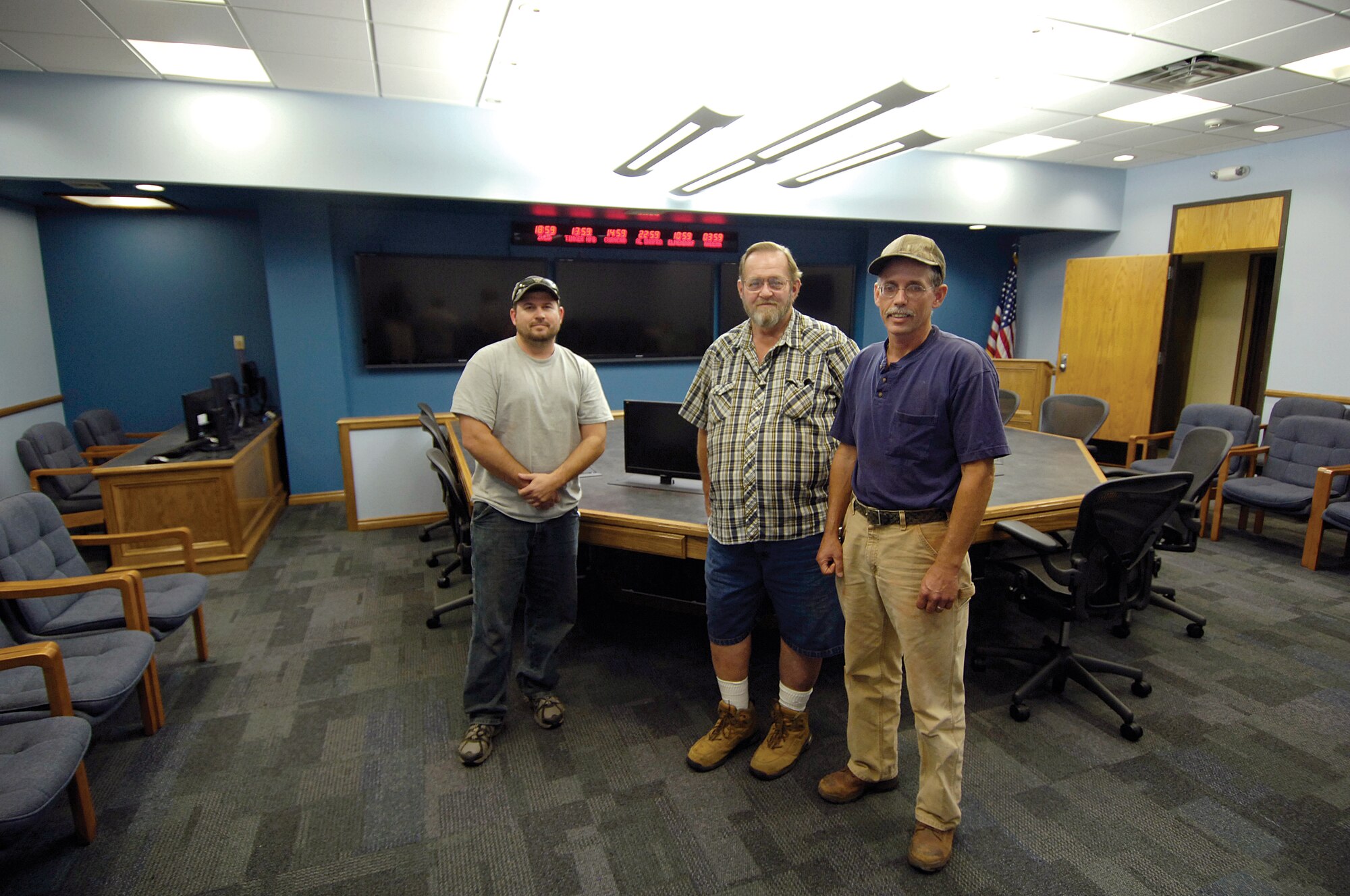 Members of the 552nd Eagle Team stand in the 552nd Battle Cab war room they gutted then rebuilt into a modern, spacious environment for senior leadership to work during emergencies or exercises.  Aaron Price, Chuck Stevens and Chris Coffman, from left, plus Hunter Stanbaugh, not pictured, transformed the area with pop-up computers in a new  hand-built central table,  a raised ceiling, non-glare lighting and more room for a gallery row that before made a tight squeeze for those seated at the table.  (Air Force photo by Margo Wright)