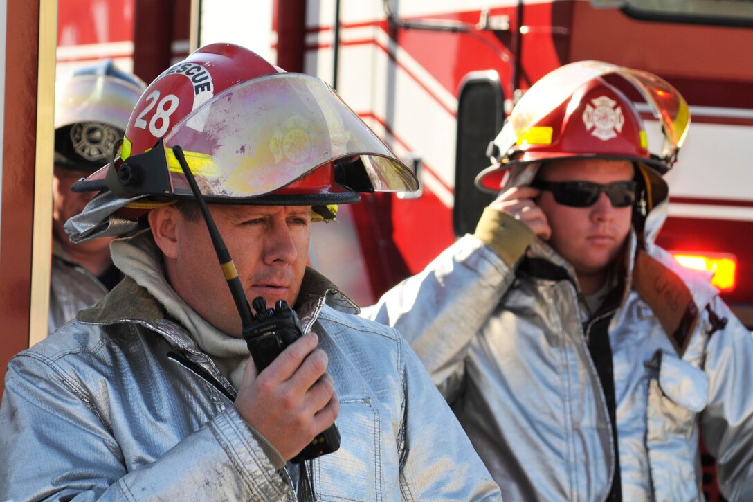 U.S. Air Force retired Master Sgt. Brian Runyon, left, makes a call over a radio during a fuel spill exercise while Staff Sgt. Taylor Webb looks on at the 182d Airlift Wing, Peoria, Ill. on Sep. 8, 2012. (U.S. Air Force photo by Airman 1st Class Zachary Morgason/Released).