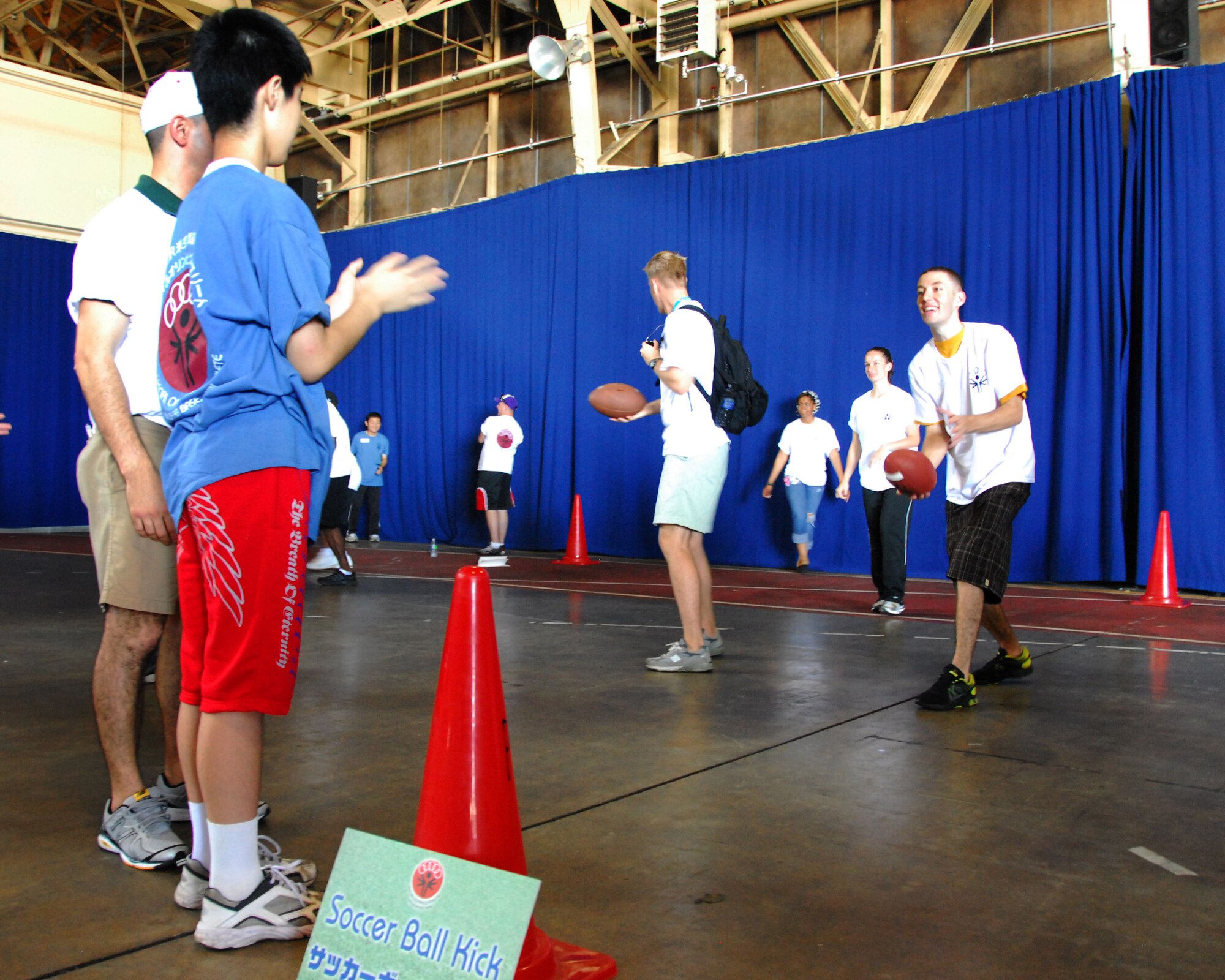 Yeaoman 3rd Class James Hughes, a native of San Angelo, Texas, and assigned to the "Fighting Tigers" of Patrol Squadron 8, throws a football to Special Olympian Yuuki Nakagawara, during the 2012 Misawa Special Olympics at Naval Air Facility Misawa, Japan, Sept. 15, 2012. The mission of Special Olympics is to provide year-round sports training and athletic competition in a variety of Olympic-type sports for children and adults with intellectual disabilities. This gives them continuing opportunities to develop physical fitness, demonstrate courage, experience joy and participate in a sharing of gifts, skills and friendship with their families, other Special Olympic athletes and the community. (U.S. Navy photo by Mass Communication Specialist 2nd Class Pedro A. Rodriguez/Released)
