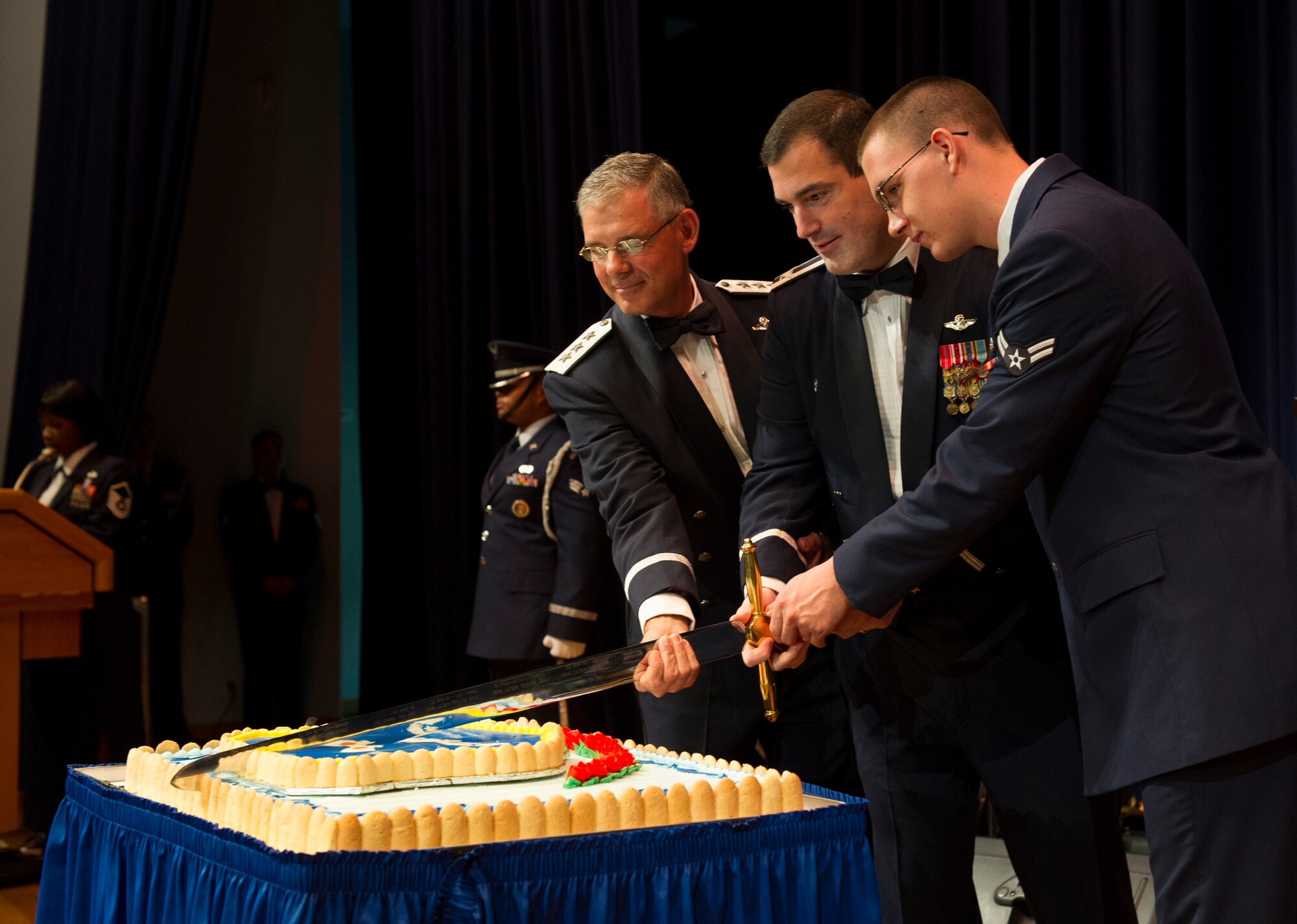 YOKOTA AIR BASE, Japan -- Lt. Gen. Sam Angelella, U.S. Forces, Japan, and 5th Air Forces commander, left, Col. Mark August, 374th Airlift Wing commander, center, and Airman 1st Class Jeffrey Robbins, 374th Force Support Squadron food specialist, cut the cake as part of the opening ceremony for the Air Force ball at Yokota Air Base, Japan, Sept. 15, 2012. During the ceremony, the most senior and most junior Air Force members in attendance receive the first two slices of cake. (U.S. Air Force photo by Senior Airman Andrea Salazar)