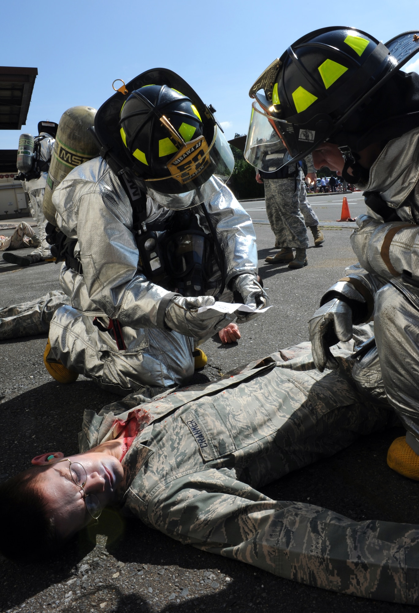 U.S. Air Force firefighters from the 35th Civil Engineer Squadron read a simulated victim's inject card to see what injuries he sustained during an Emergency Management Exercise at Misawa Air Base, Japan, Sept. 17, 2012. The wing was tested on its response to an increased terrorist threat, accountability procedures and response to a mass casualty event. Members of the 35th Fighter Wing conducted the EME as part of their Combined Unit Inspection. (U.S. Air Force photo by Airman 1st Class Kia Atkins/Released)
