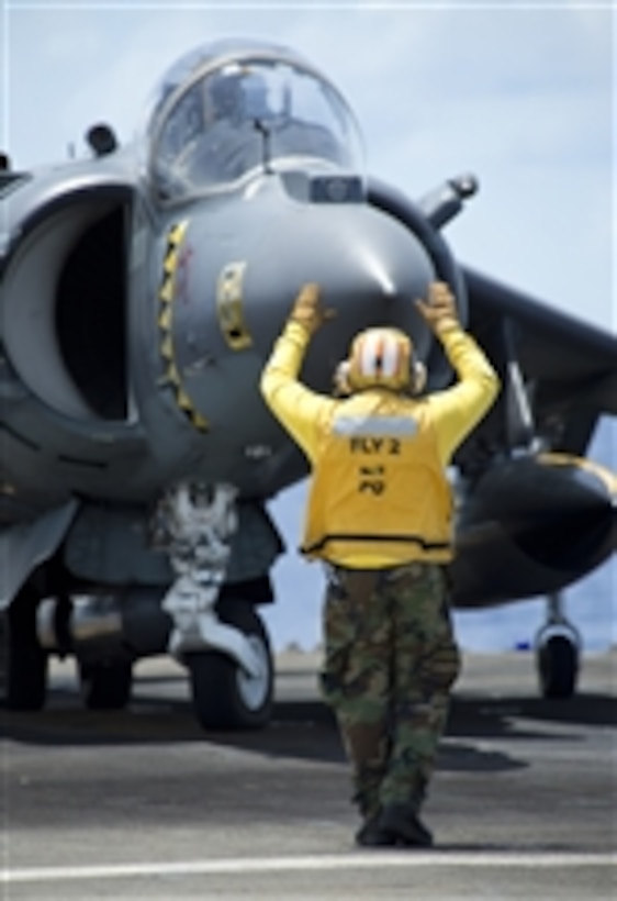 A flight deck crewman directs the pilot of an AV-8B Harrier jet aircraft during flight operations aboard the amphibious assault ship USS Bonhomme Richard (LHD 6) in the Philippine Sea on Sept. 15th, 2012.  The Bonhomme Richard Amphibious Ready Group, along with the 31st Marine Expeditionary Unit, is participating in a certification exercise.  The Harrier is attached to Marine Attack Squadron 542.  