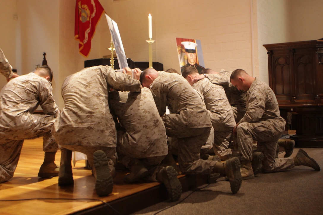 Marines with 2nd Law Enforcment Battalion huddle together in silence in rememberance of Sgt. Joshua Ashley during a memorial ceremony at the Protestant chapel aboard Marine Corps Base Camp Lejeune Sept. 12.  Ashley, a military dog handler, was killed in Afghanistan in July while conducting operations in Helmand province. (Photo by Sgt. Bobby J. Yarbrough)